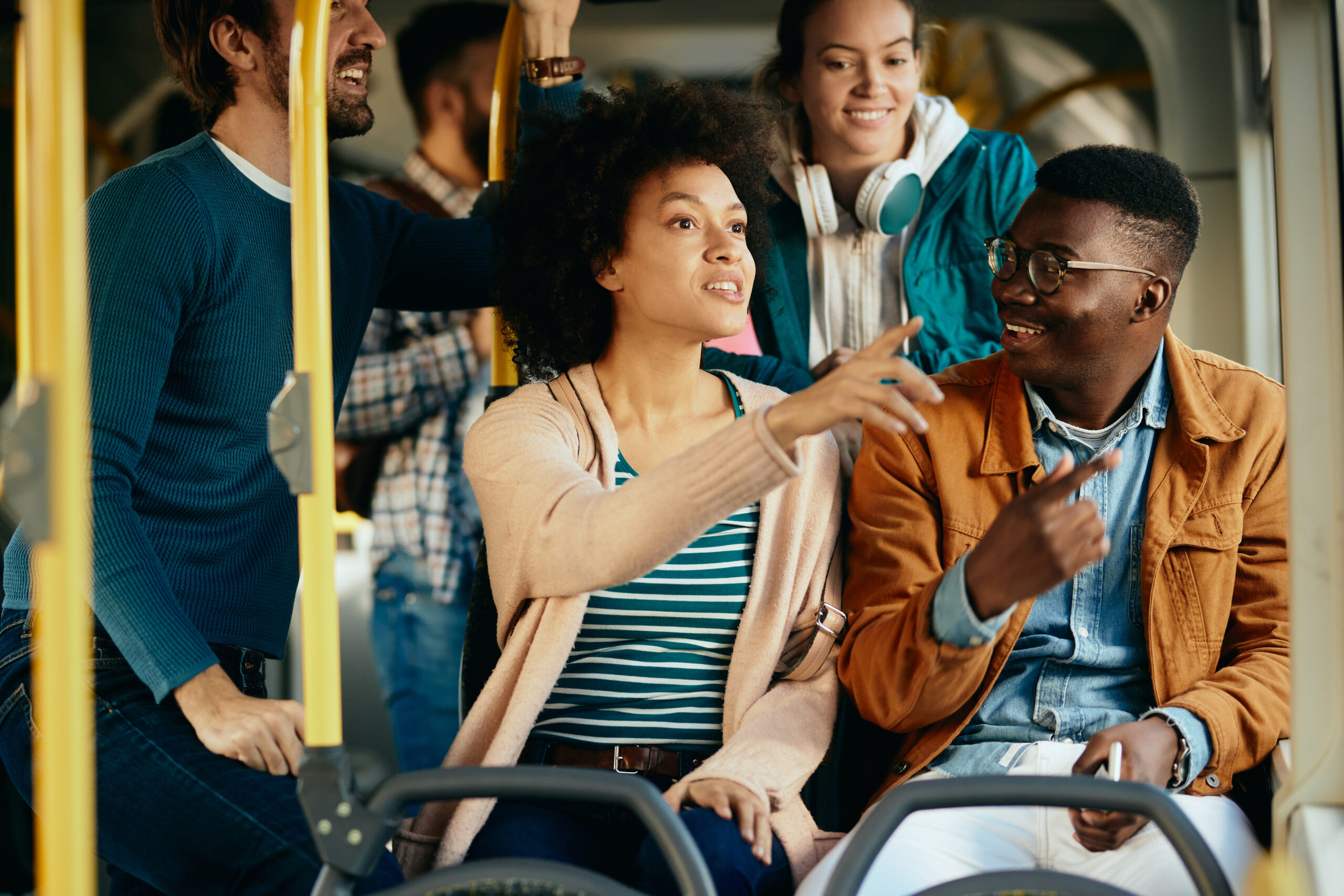 Happy African American couple pointing at something through the window while traveling by public transport.